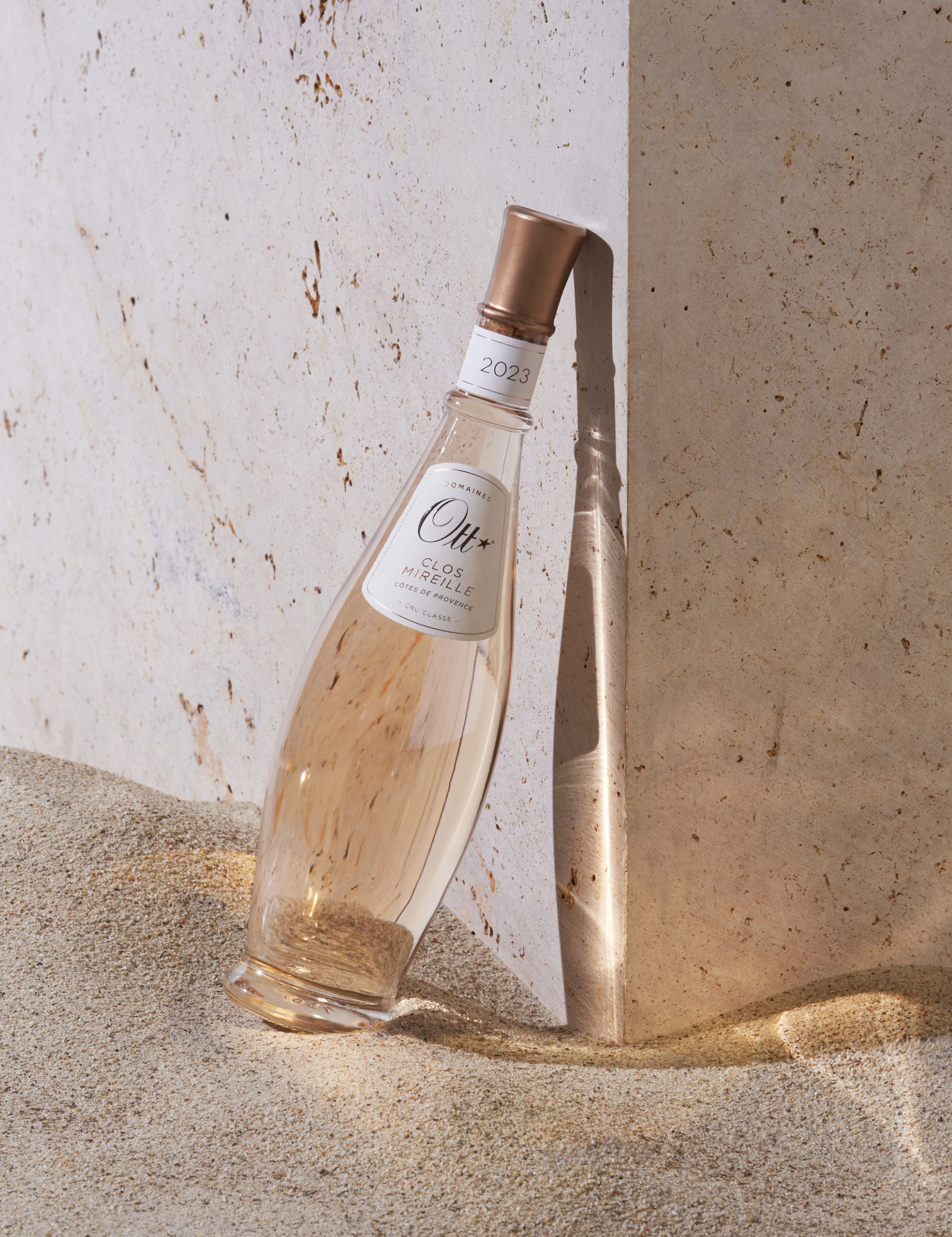 une-bouteille-clos-mireille-rose-dans-le-sable-contre-un-mur